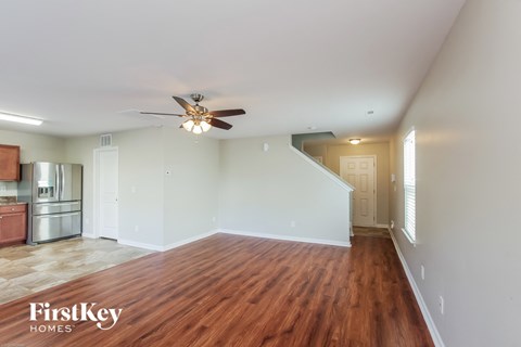 an empty living room with wood flooring and a ceiling fan