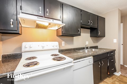 A kitchen with black cabinets and a white stove top oven.
