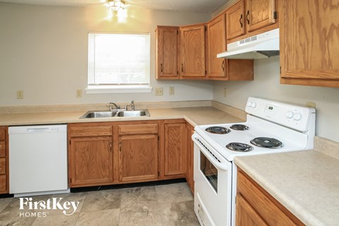 A kitchen with wooden cabinets and a white stove top oven.