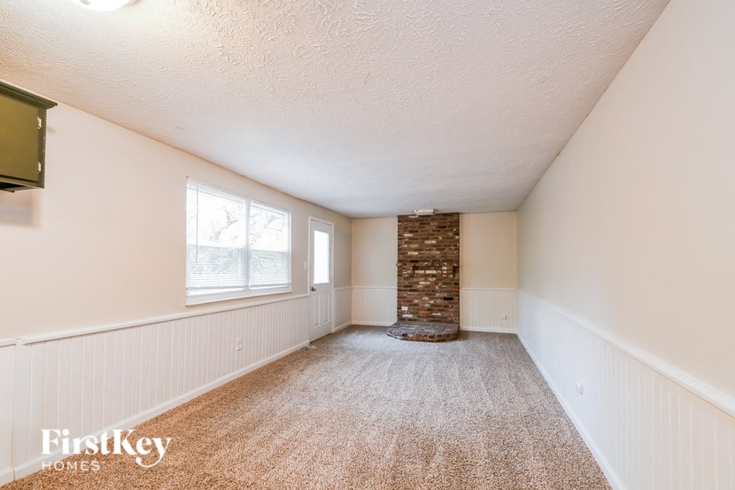 A room with a carpeted floor and a stone pillar in the middle.