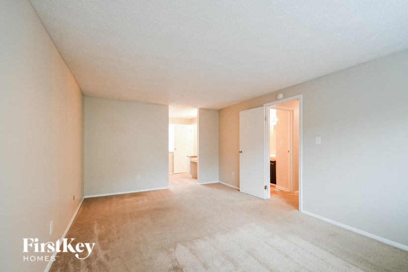 A spacious empty room with a carpeted floor and white walls.