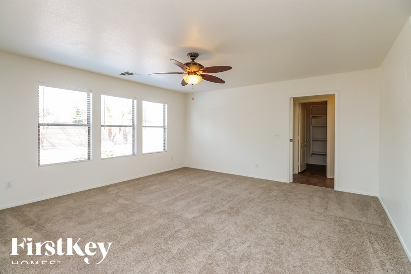 A spacious room with a ceiling fan and a door leading to another room.