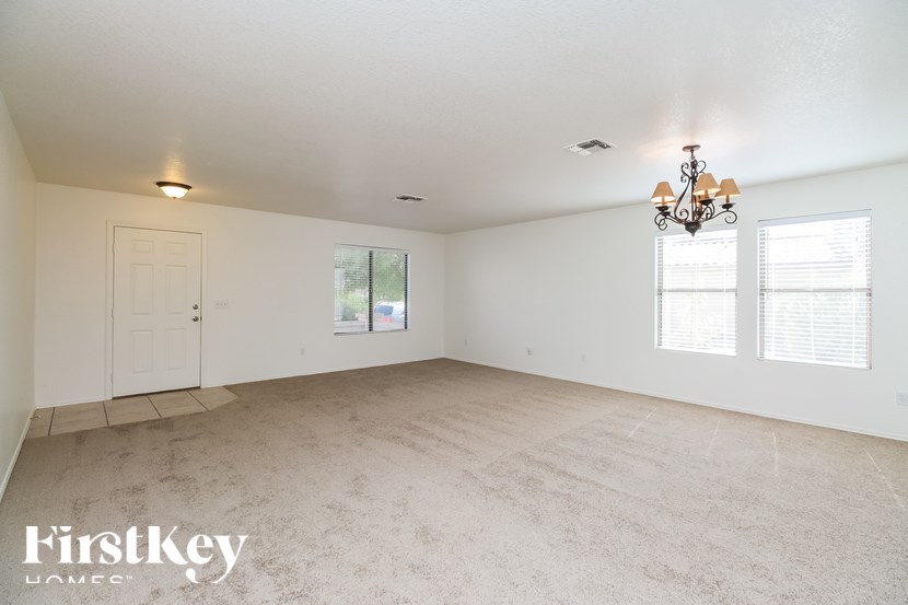 A room with a chandelier, a door, and a window with blinds.