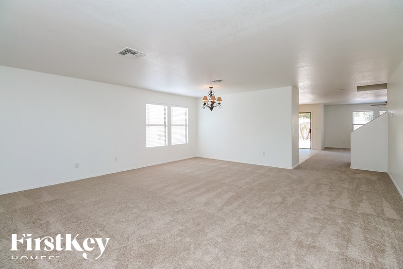 A spacious room with a carpeted floor and a chandelier hanging from the ceiling.