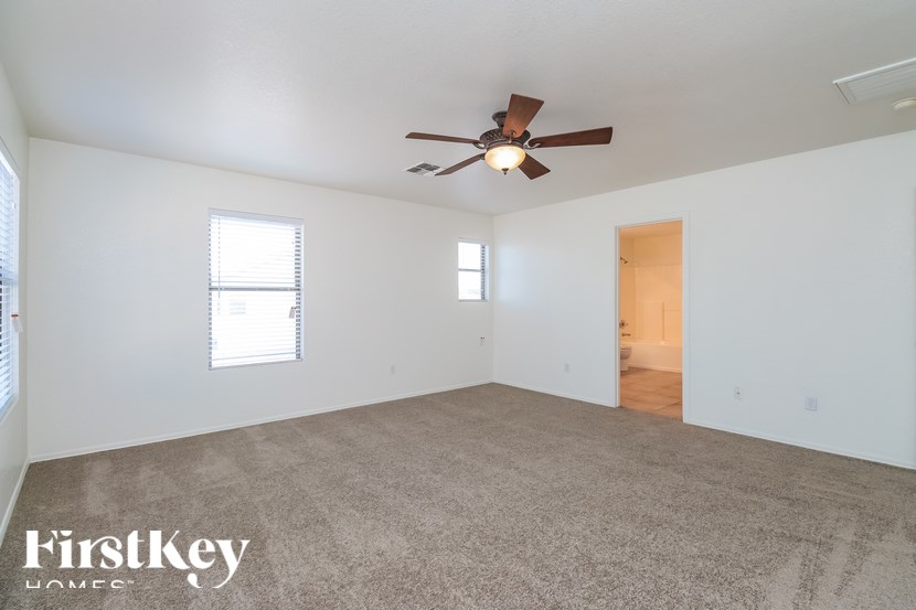 A spacious room with a ceiling fan and carpeted floor.