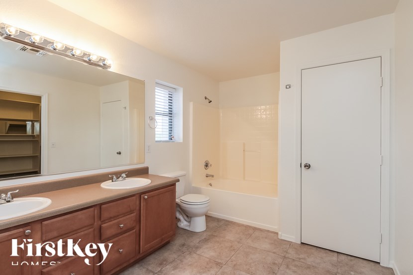 A bathroom with a mirror, two sinks, and a toilet.
