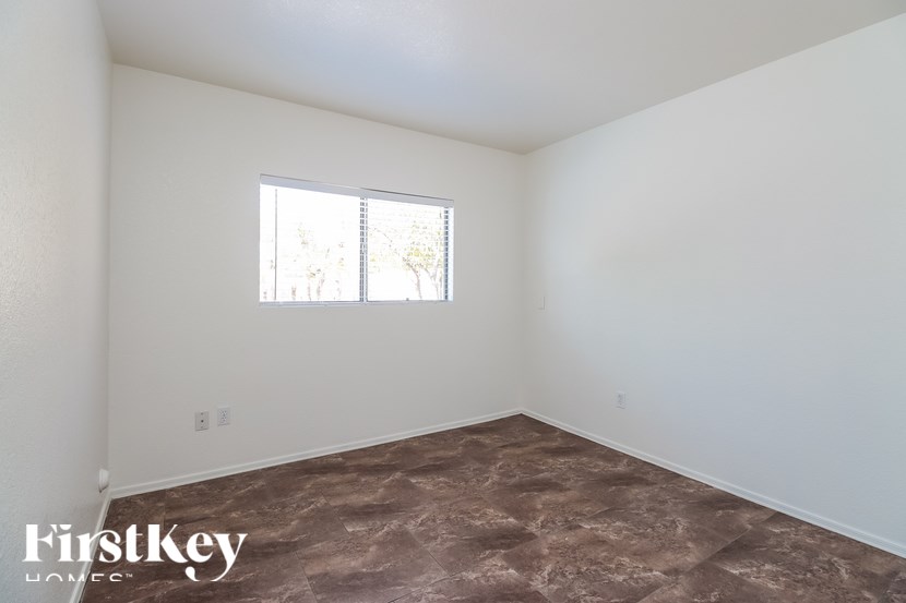 A room with a brown floor and a window with blinds.