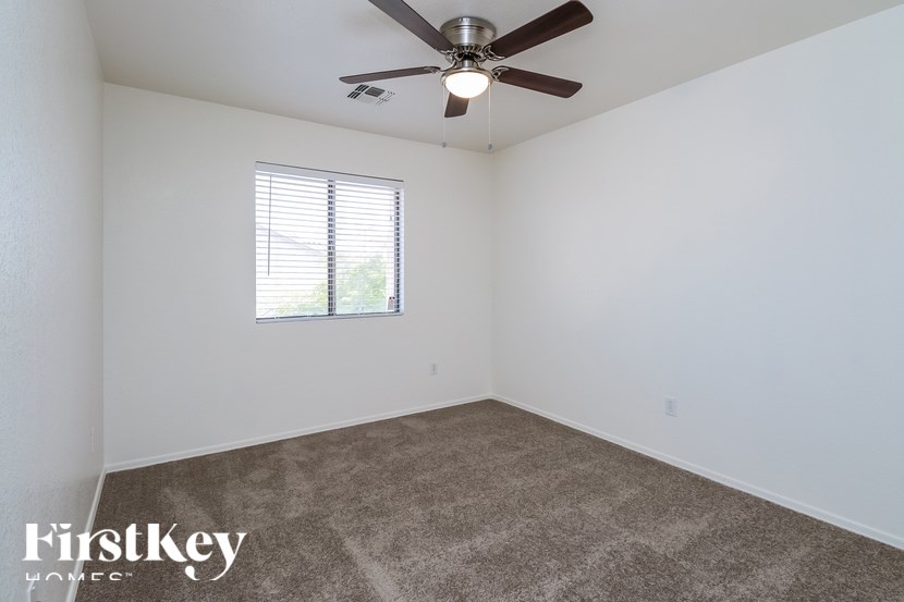A room with a ceiling fan and a window with blinds.
