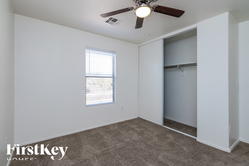 A room with a ceiling fan and a window with blinds.