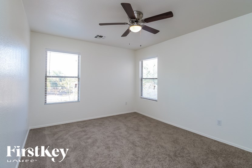 A room with a ceiling fan and two windows.