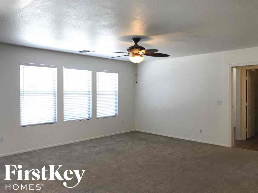 A room with a ceiling fan and three windows.