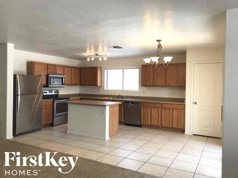 A kitchen with a refrigerator, microwave, oven, and sink.
