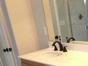 A bathroom with a white countertop and wooden cabinets.