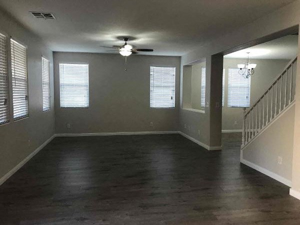 A spacious room with a staircase on the right and a ceiling fan in the middle.