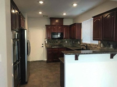 A kitchen with dark brown cabinets and a black refrigerator.