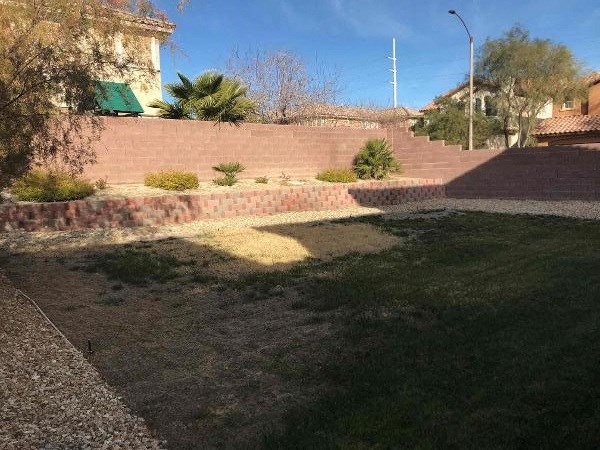 A grassy area with a brick wall and a lamp post in the background.