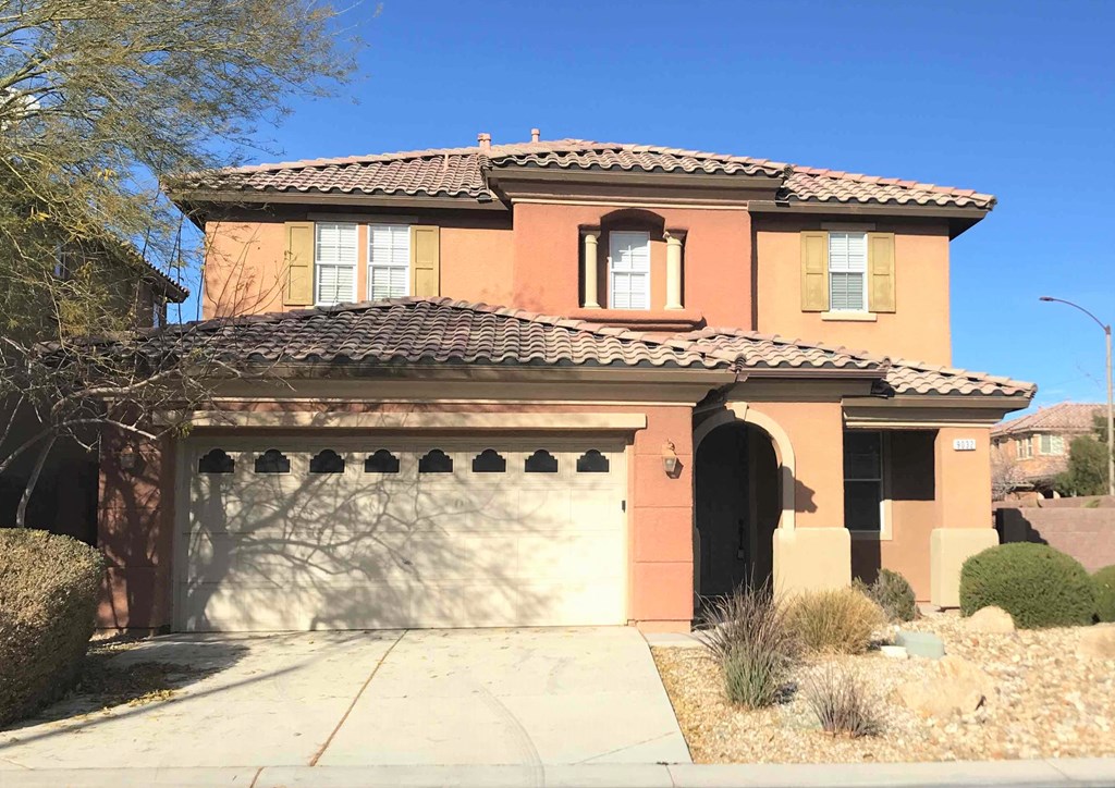 A house with a brown roof and tan walls with a garage door.