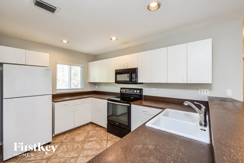 a kitchen with white cabinets and a sink and a refrigerator