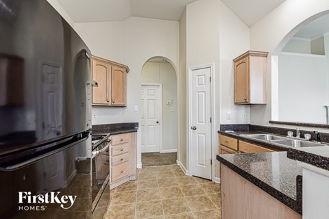 A kitchen with a black fridge and a black counter top.