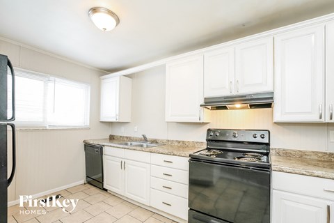 A kitchen with a black stove top oven and white cabinets.