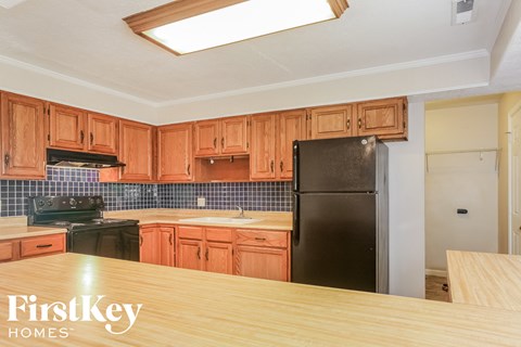 A kitchen with wooden cabinets and a black fridge.