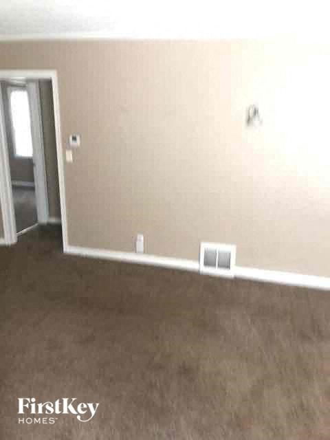 an empty living room with a brown carpet and a door