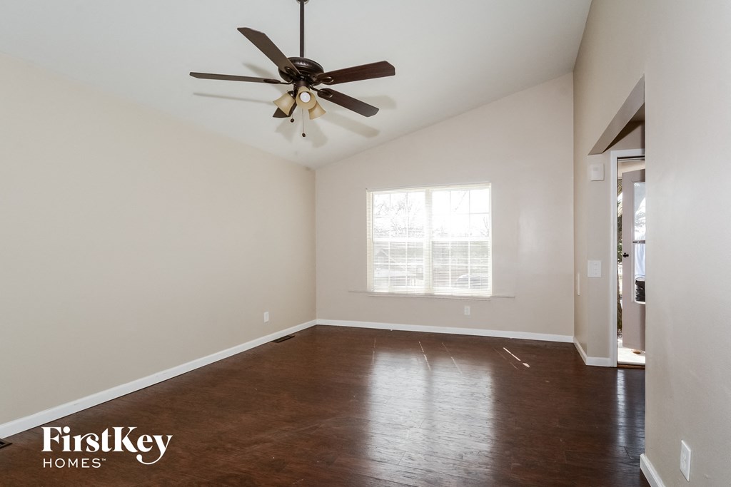 an empty living room with a ceiling fan and a window