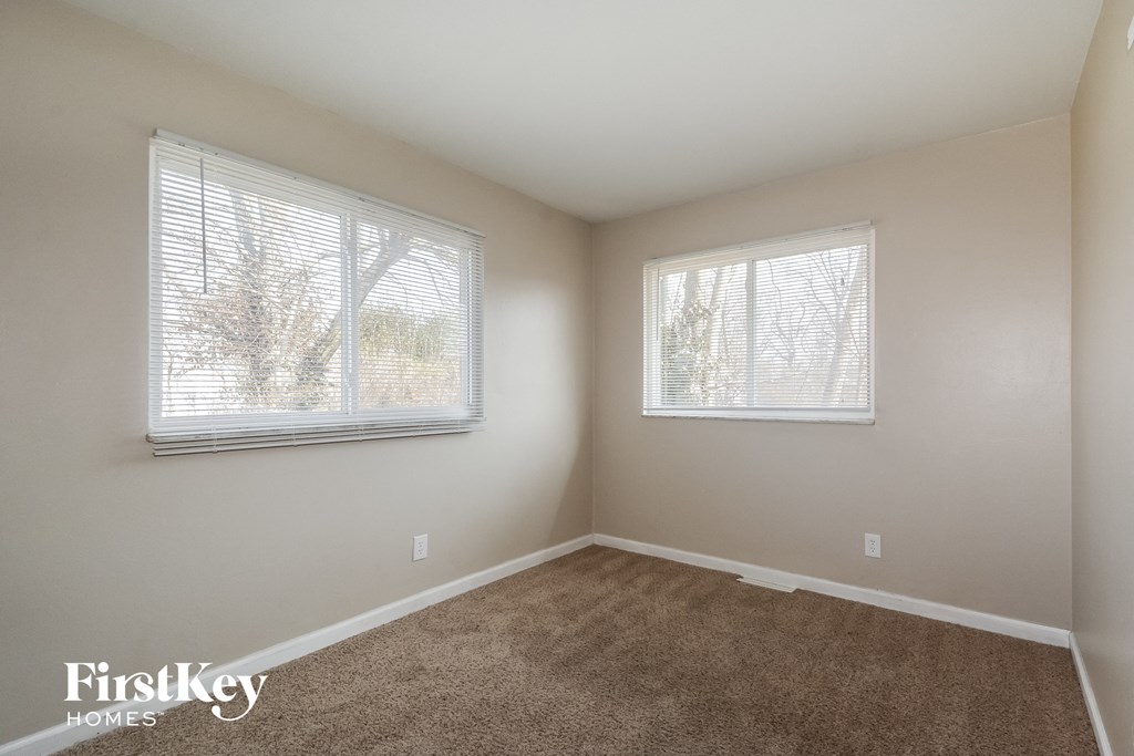 a room with carpet and two windows