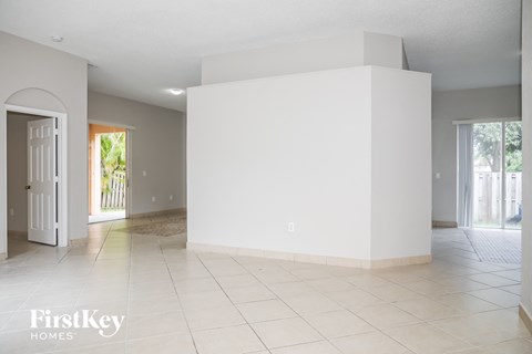 A large empty room with a white tile floor and a white wall.