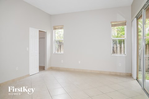 A spacious room with a sliding glass door leading to a balcony.