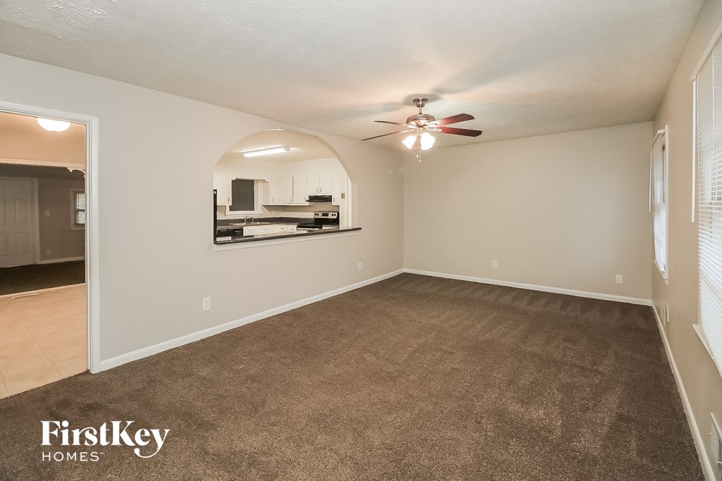 an empty living room with carpet and a ceiling fan