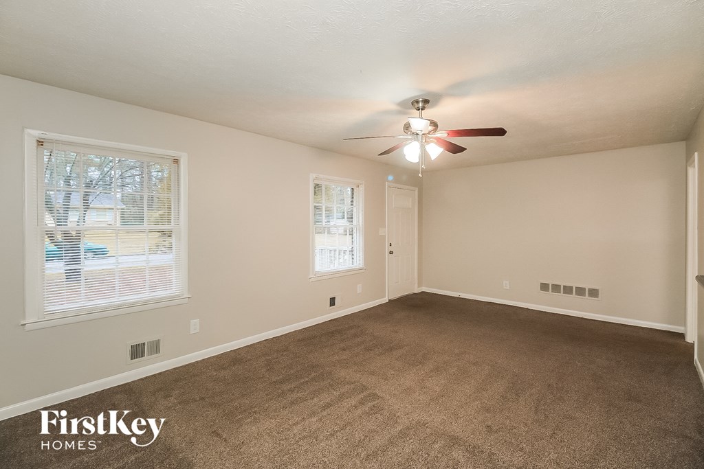 an empty living room with carpet and a ceiling fan