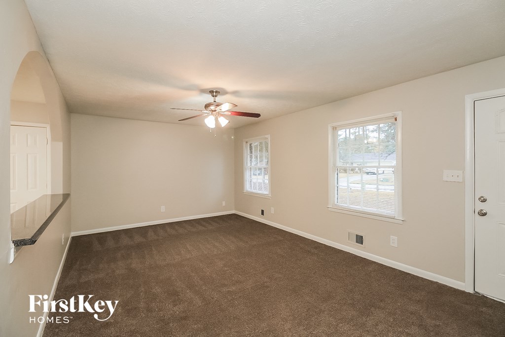 an empty living room with a ceiling fan and a window
