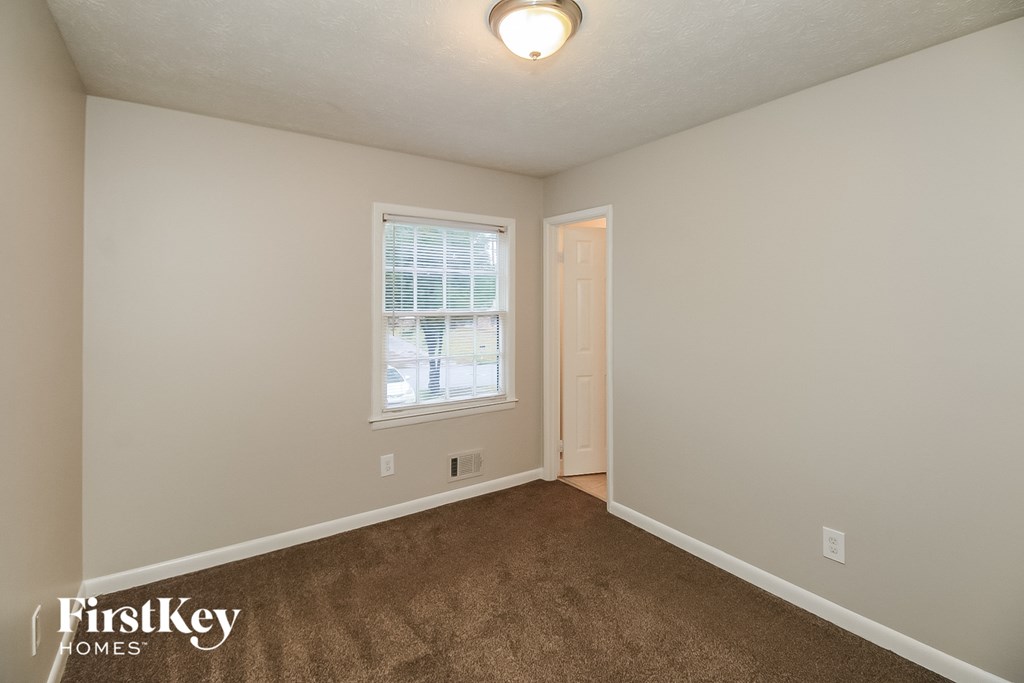 a bedroom with a carpeted floor and a window and a door