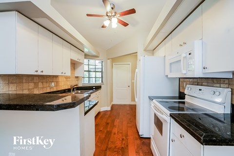 A kitchen with white cabinets and black countertops.