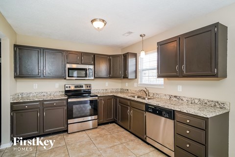 a kitchen with dark cabinets and granite counter tops and stainless steel appliances
