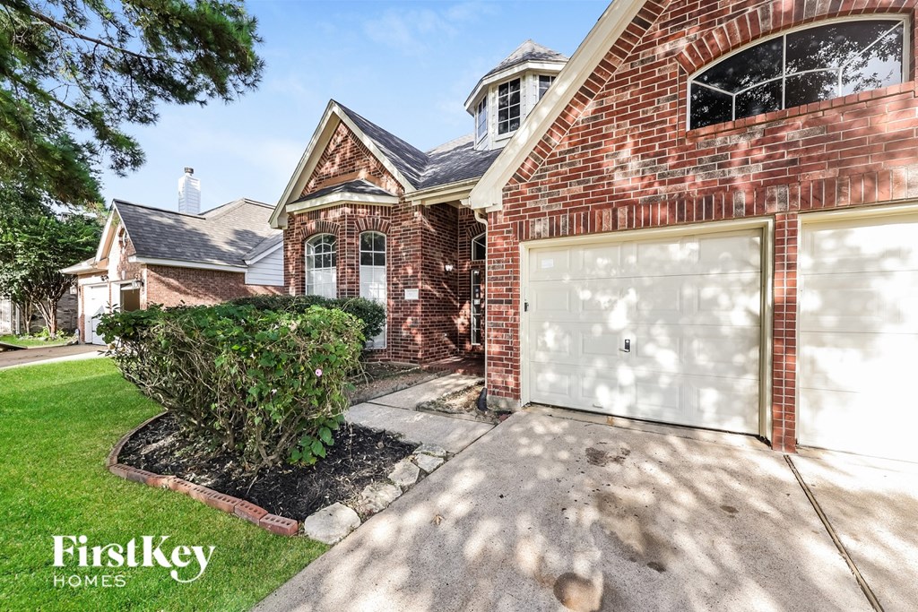 A brick house with a white garage door and a sign that says "FirstKey Homes".