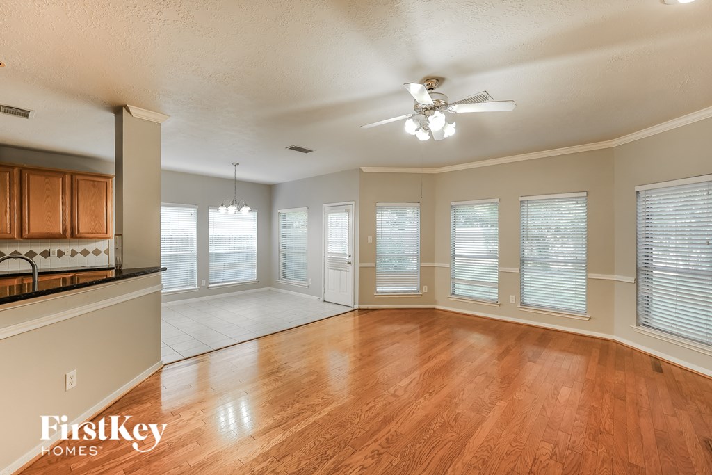 A spacious room with wooden floors and a ceiling fan.