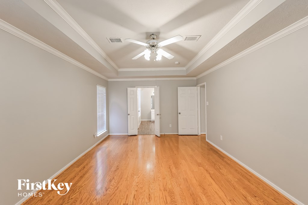 A spacious room with wooden floors and a ceiling fan.