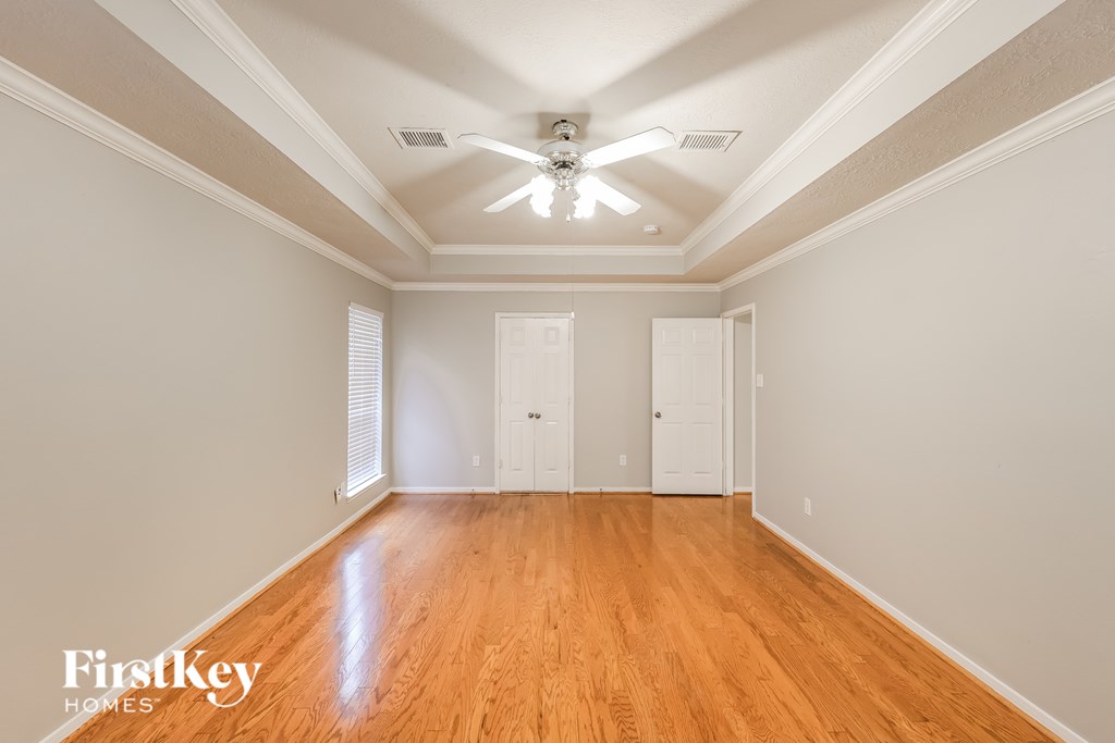 A spacious room with wooden floors and a ceiling fan.