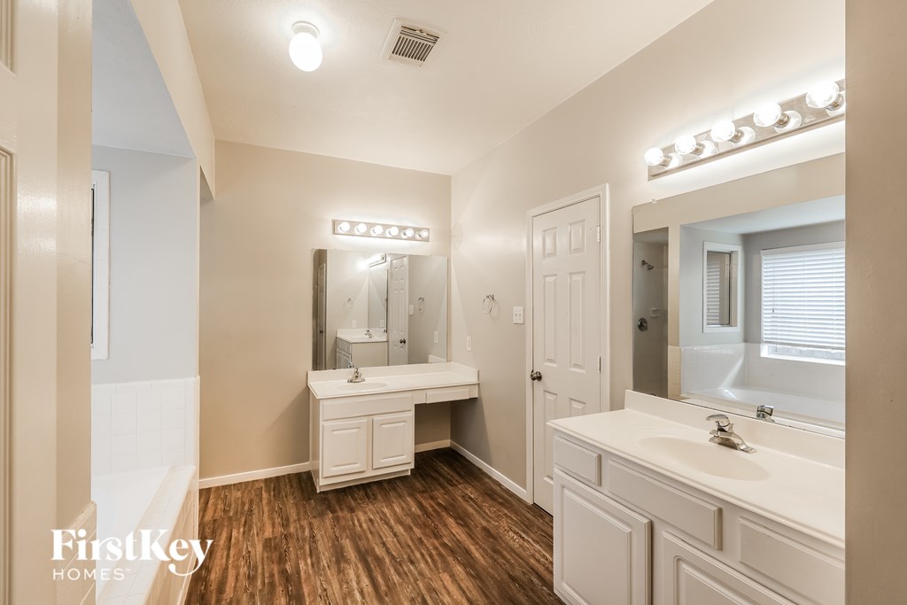 A bathroom with a vanity, mirror, and lights.