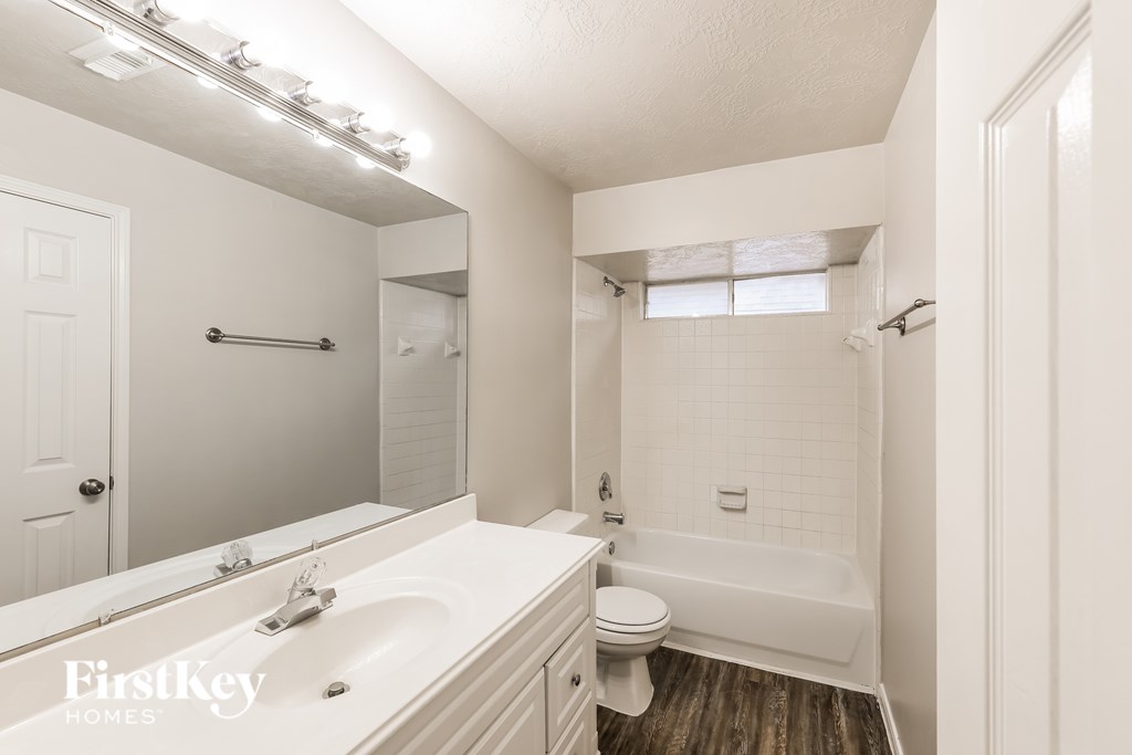 A white bathroom with a tub, toilet and sink.