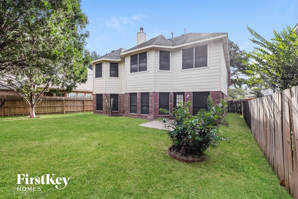 A house with a lawn and a fence in front of it.