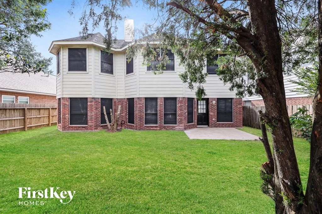 A house with a large front yard and a tree in the foreground.