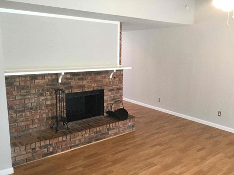 a living room with a brick fireplace and a wooden floor