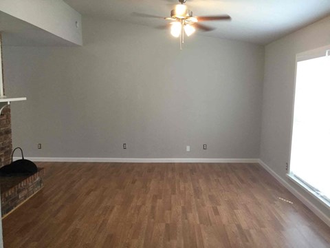 an empty living room with wood floors and a ceiling fan