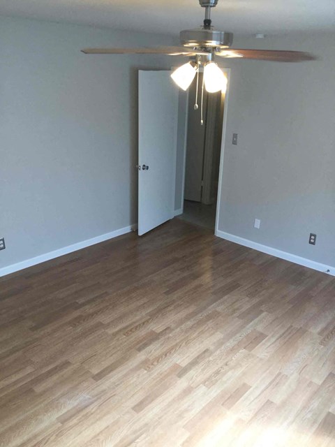 a living room with wood flooring and a ceiling fan