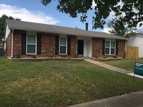 a small brick house with a lawn and a sidewalk