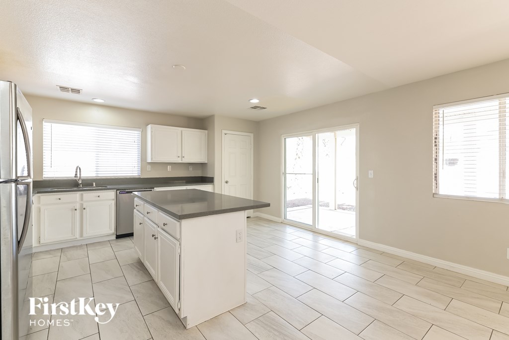 A kitchen with white cabinets and a tile floor.