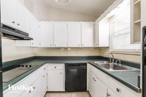 A kitchen with white cabinets and a black dishwasher.